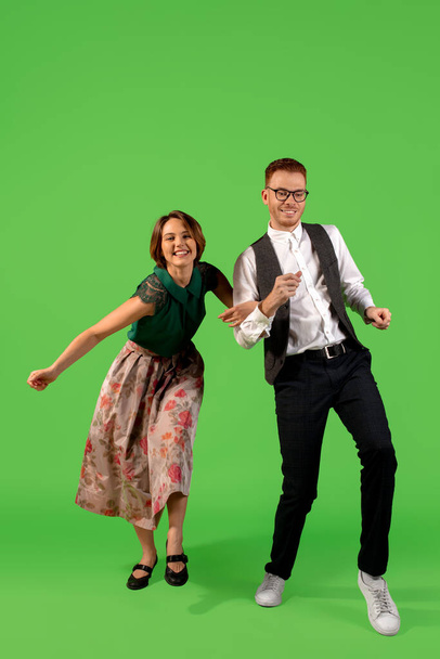 Old-school fashioned young woman dancing isolated on green background - 写真・画像