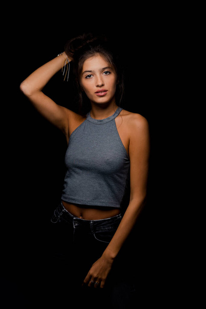 Studio body shot of an attractive woman posing in stylish clothes while posing against black background - Foto, immagini