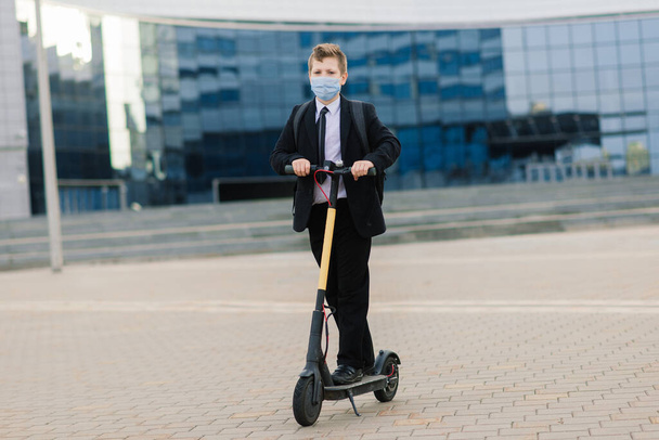 Estudante bonito com máscara protetora dirigindo uma scooter na cidade. - Foto, Imagem