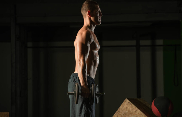 Oldalnézet egy testépítő csinál nehéz súly edzés bicepsz - Fotó, kép