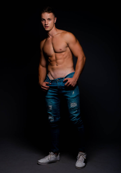 Torso shot of a cool shirtless guy wearing trendy blue jeans - Fotó, kép