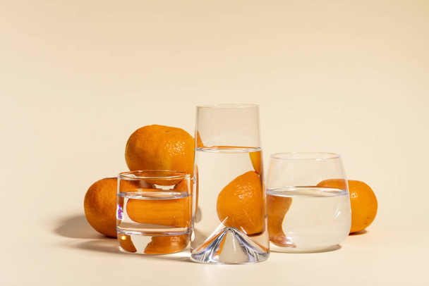 A selective focus closeup of tangerines and glasses on a peach backgroun - Fotografie, Obrázek