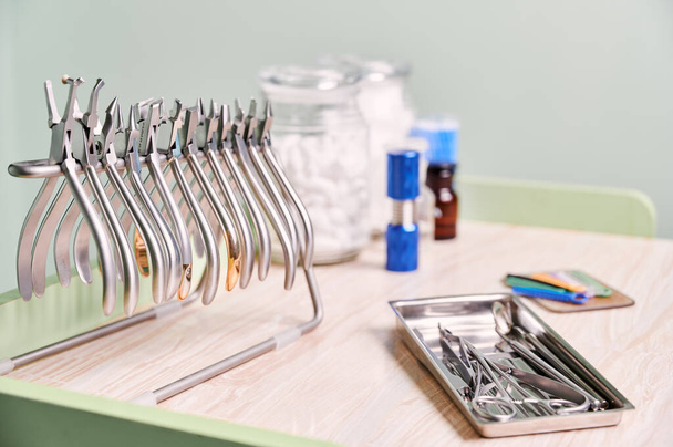Set van diverse roestvrijstalen instrumenten voor beugels en tandheelkundige behandeling. Zilveren tang, snijplotters, verhuizers, tang, andere orthodontische gereedschappen op het bureau in de tandheelkundige kliniek. Begrip tandheelkunde. - Foto, afbeelding