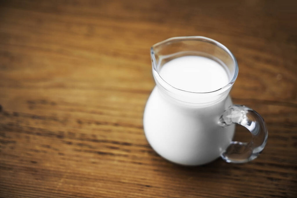 fresh milk in glasses jug on wooden board background. empty copy space for insription. - Photo, Image