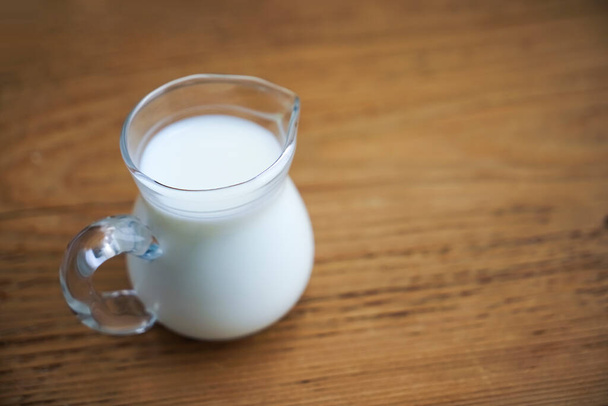 fresh milk in glasses jug on wooden board background. empty copy space for insription. - Foto, immagini