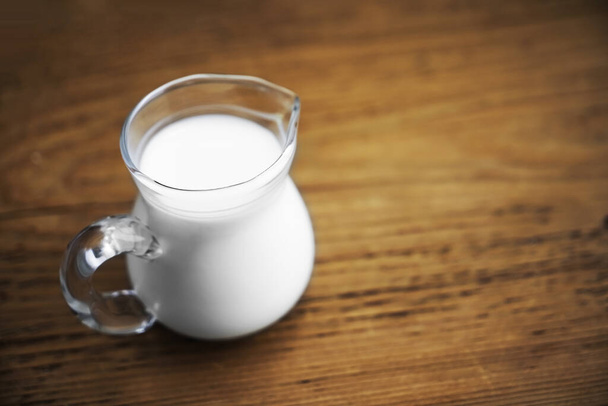 fresh milk in glasses jug on wooden board background. empty copy space for insription. - Фото, зображення