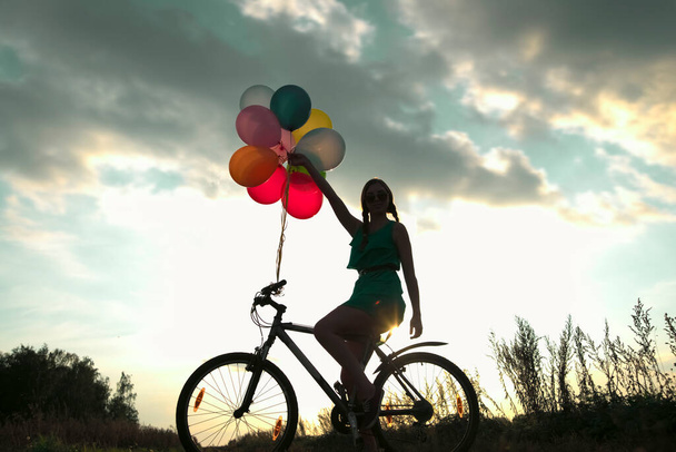 Young Girl in sexy dress  riding bicycle flying air balloons  - Photo, Image