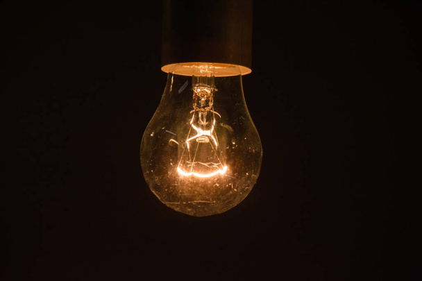 Glowing light bulb on black background with copy space close up. - Foto, afbeelding