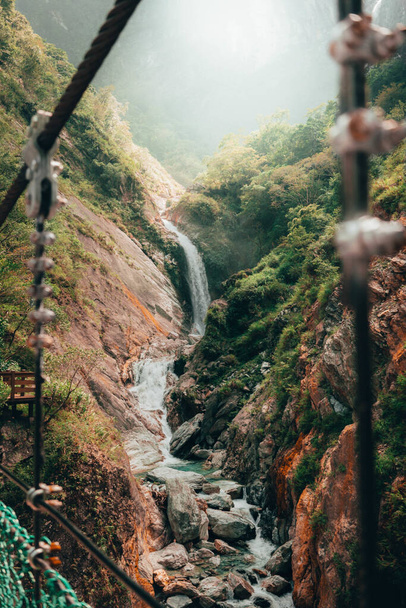 A vertical shot of a small waterfall through rocks in Taiwan - Фото, зображення