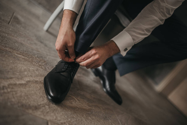 A closeup shot of a groom tying his shoes on the wedding day - Photo, Image