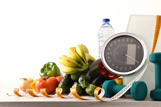 Healthy food and sport background on a white wooden table with scale and measuring tape white isolated background. Front view. Horizontal composition. - Zdjęcie, obraz