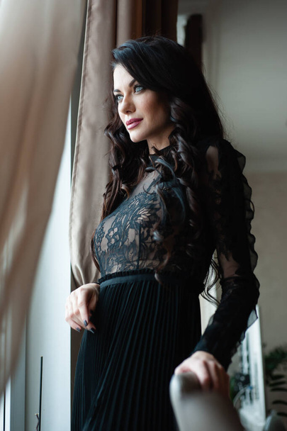 Чуттєва красива брюнетка жінка позує в довгій чорній сукні
. - Фото, зображення
