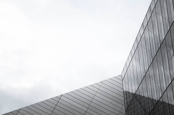 Een lage hoek uitzicht van een all-glass wolkenkrabber onder een sombere lucht in de stad - Foto, afbeelding