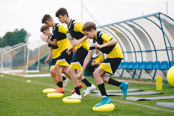Sportegyensúly tréning. Stabilitási fociedzés az egyensúlyi párnán. Fiatal focisták készségfejlesztő. Fiatal férfi sportolók edzenek a pályán. Fűfutball-felszerelés a gyakorlótéren - Fotó, kép