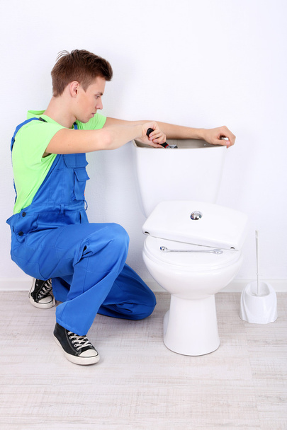 Plumber with toilet plunger on light background - Photo, Image