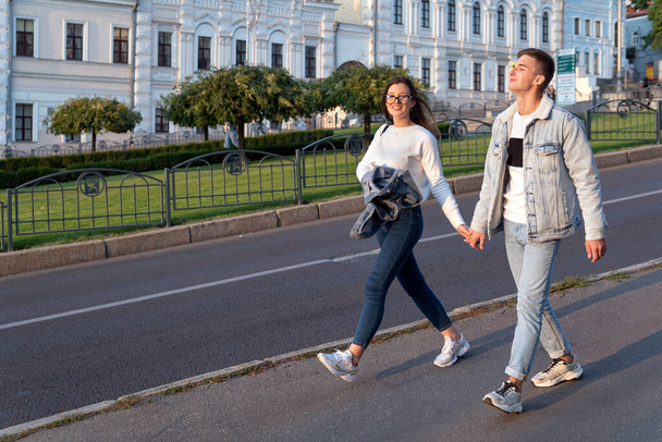 Любящая молодая пара, гуляющая по городу, держась за руки. - Фото, изображение