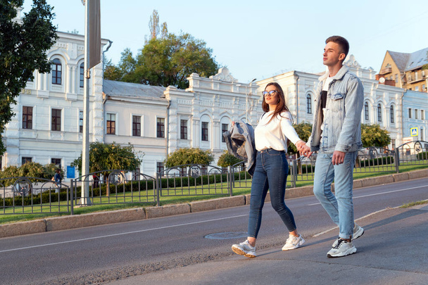 Αγαπάω το νεαρό ζευγάρι που περπατά στην πόλη κρατώντας τα χέρια. Ραντεβού στα τυφλά. - Φωτογραφία, εικόνα
