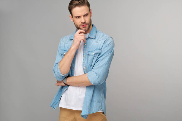 Portrait of young handsome caucasian man in jeans shirt over light background - Foto, Imagen