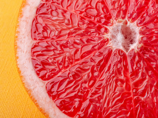 Slice of ripe juicy grapefruit on a yellow background macro shot. Ingredient for fruit desserts. Tasty vegetarian food, slimming diet and vitamin healthy eating. Close-up. Front view. - Zdjęcie, obraz
