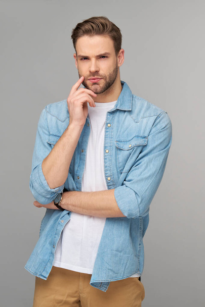 Portrait of young handsome caucasian man in jeans shirt over light background - Foto, imagen