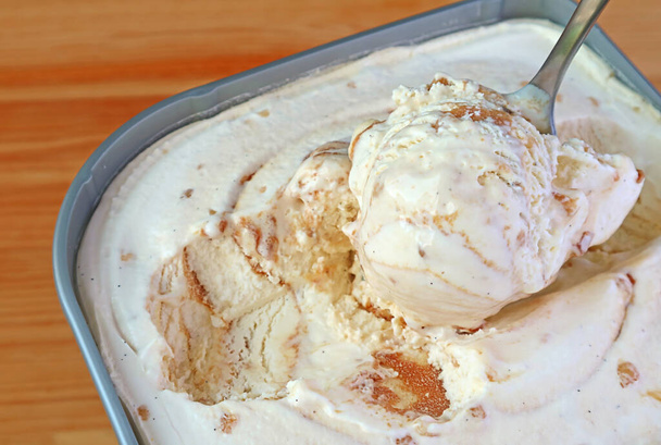Closeup de uma colher Escavar caramelo selecionável Macadâmia Nut Ice Cream na banheira - Foto, Imagem