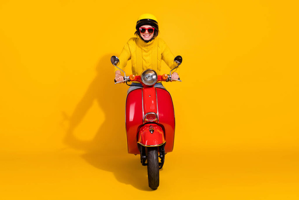 Photo portrait of girl riding red retro bike isolated on vivid yellow colored background - Fotó, kép