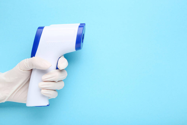 Medical infrared thermometer in doctor hand on blue background - Foto, afbeelding
