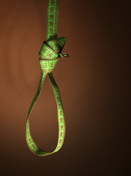 Tape measure noose on brown background - diet concept - Фото, изображение