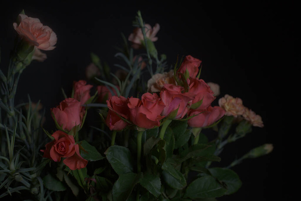 Buquê de rosas vermelhas minúsculas e cravos de laranja em um fundo preto - Foto, Imagem