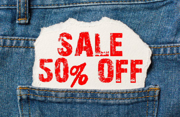 Sale 50 off on white paper in the pocket of blue denim jeans - Φωτογραφία, εικόνα