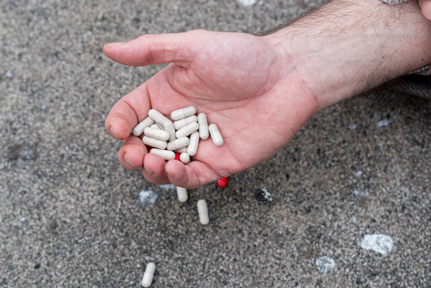 Main d'homme tenant plusieurs pilules. Accès aux médicaments sur ordonnance et surdosage accidentel possible - Photo, image
