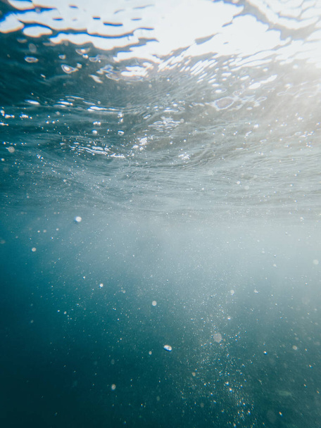 Kristal berrak denizin altında dikey fotoğraf. Yukarıdan gelen ışık huzmeleri. - Fotoğraf, Görsel