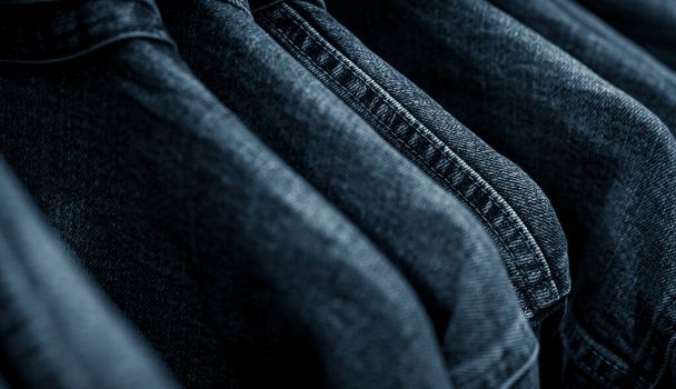 Focus sélectif sur les jeans veste suspendus sur rack dans le magasin de vêtements. Jeans en denim avec motif de jeans. Industrie textile. Jeans mode et concept shopping. Concept vestimentaire. Veste en denim sur rack à vendre. - Photo, image