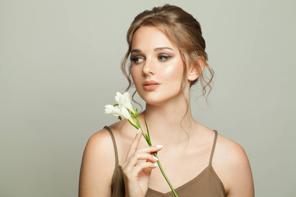 Mujer encantadora con piel sana sosteniendo flores blancas, cuidado de la piel y el concepto de tratamiento facial - Foto, imagen