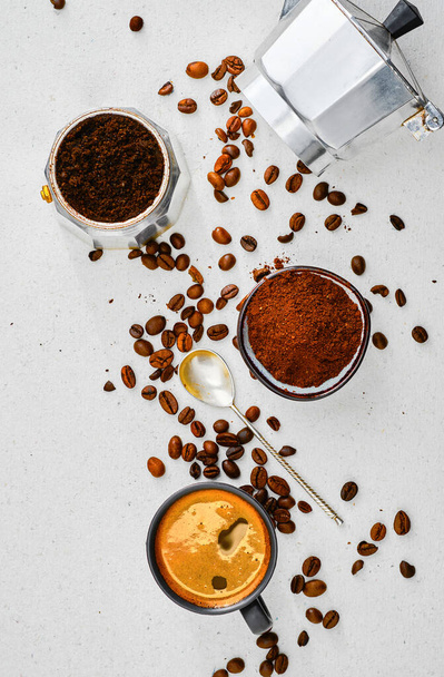 Tasse mit Ristretto, gemahlenem Kaffee im Becher und Kaffeekanne und Kaffeebohnen auf einem grauen Tisch. Draufsicht, Idee, Kaffee zu kochen - Foto, Bild