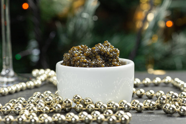 Black caviar. Black sturgeon caviar in a ceramic bowl and silver beads on a silver tray. - Photo, Image