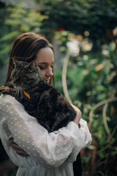 Young woman holds and embraces cat during stroll in park. - Photo, Image