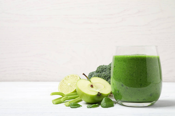 Delicious green juice and fresh ingredients on white wooden table, space for text - Foto, imagen