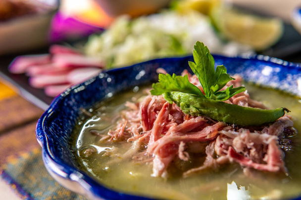 A selective focus shot of a ham and avocado soup in a blue bowl on a blurry background - Foto, afbeelding