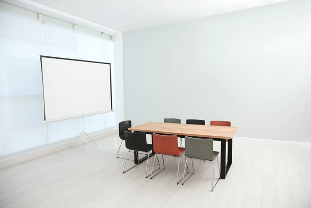 Sala de conferencias interior con mesa de madera y pantalla de proyección de vídeo - Foto, imagen