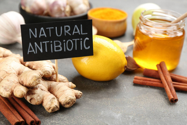 Different fresh products and card with phrase Natural Antibiotic on grey table, closeup - Valokuva, kuva