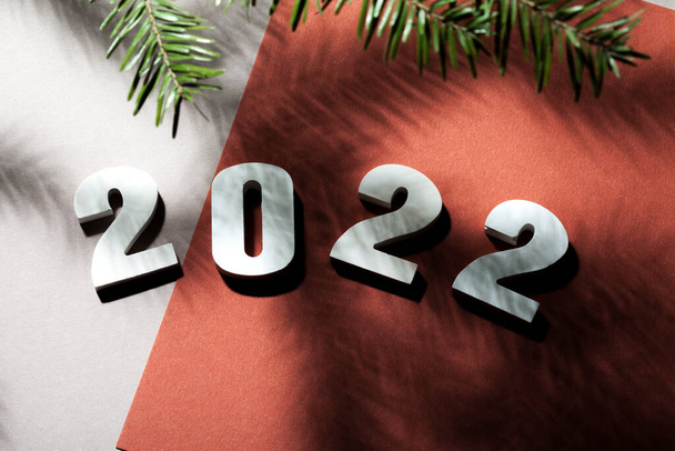 на красном фоне с деревянными белыми цифрами написано 2022 год. Тень от рождественской елки - Фото, изображение