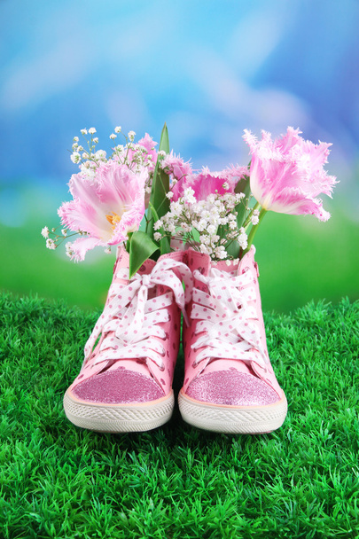 Beautiful gumshoes with flowers inside on green grass, on bright background - Foto, imagen