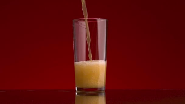 赤の背景に隔離されたガラスにオレンジジュースを入れる。ストック映像だ。健康的な食事、ビタミンC 、免疫の概念. - 映像、動画