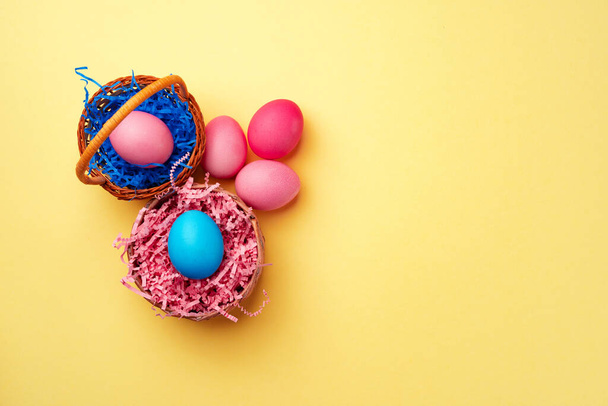Decorative nest with colorful Easter eggs on yellow background - Fotó, kép