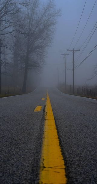A vertical blurry shot of a road on background of the fog covering the street - Photo, image