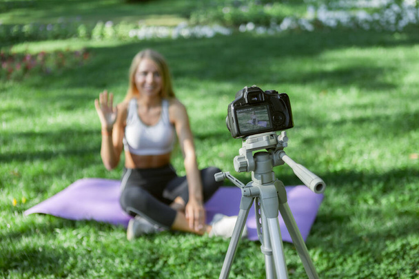 Jong vrolijk fitness model bloggen op camera in het park buiten - Foto, afbeelding