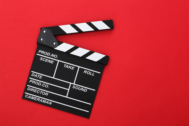 Film clapper board on red background. Cinema industry, entertainment. Top view - Photo, Image