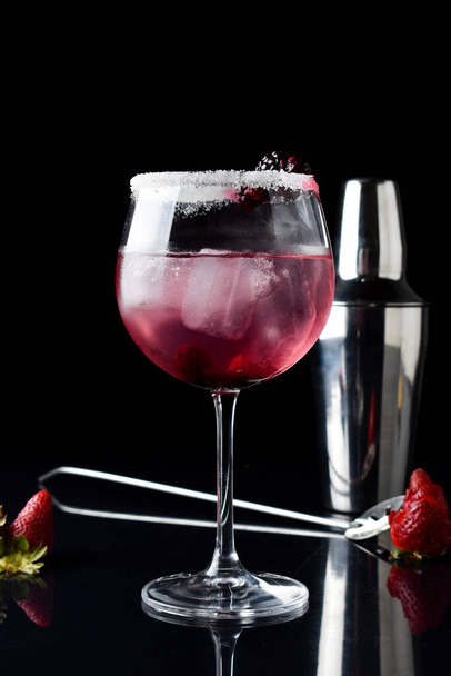Un trago vertical de un cóctel con mora, frambuesas, fresas, con una botella y una cuchara - Foto, imagen