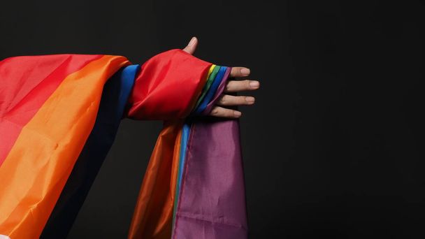 LGBTQ flag or Lesbian Gay Bi sexsual Transgender Queer or homosexsual pride Rainbow flag on black background. Represent hand symbol of freedom, peace, equality and love. LGBTQ concept - Photo, Image